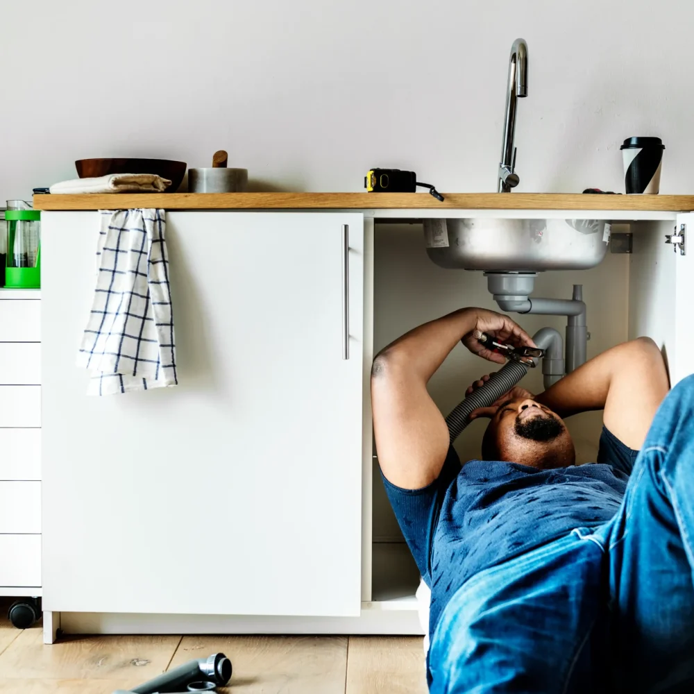 Un plombier de Bruxelles travaille sous un évier de cuisine